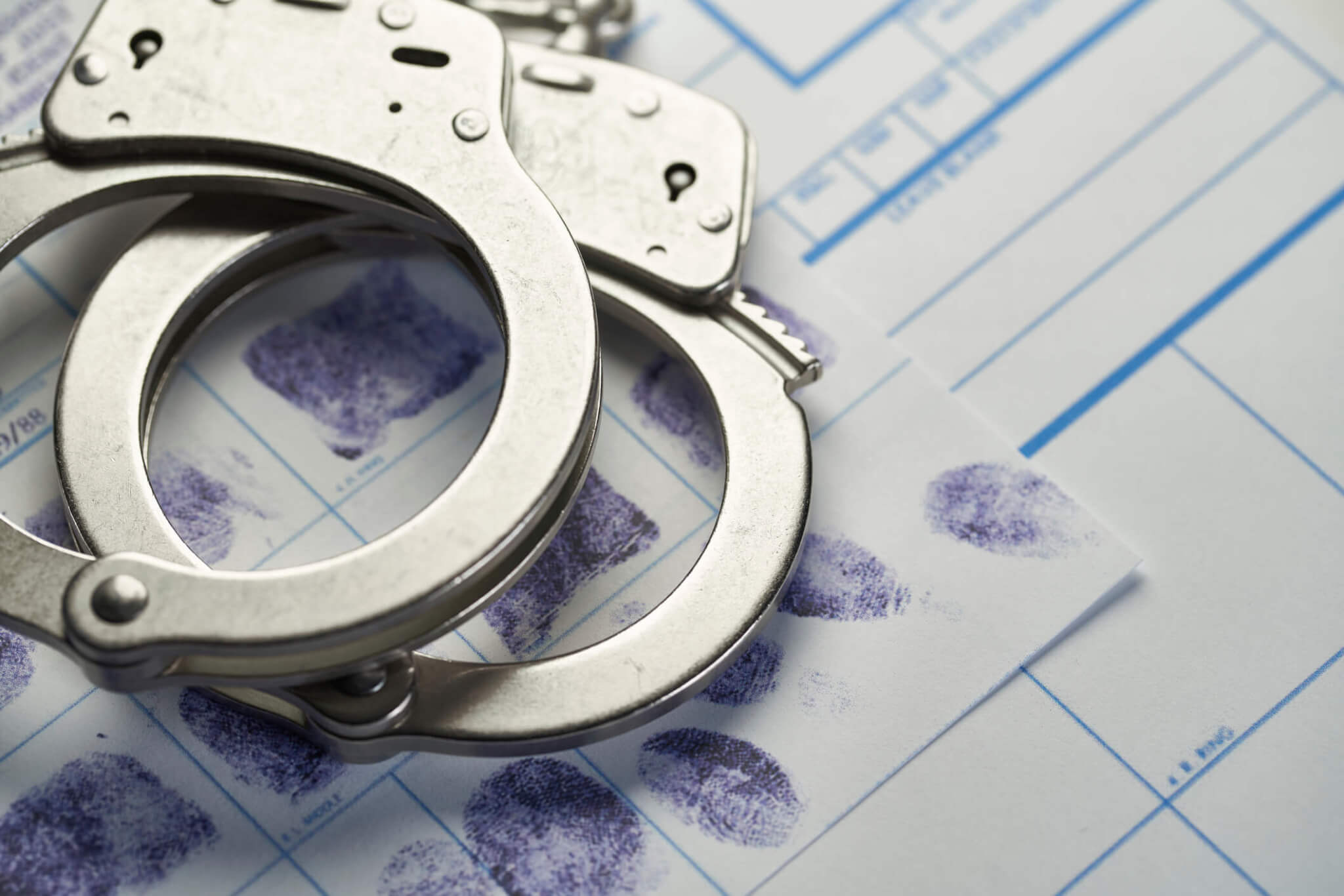 Handcuffs and fingerprints on a criminal record.