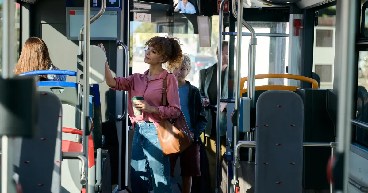 Passengers standing and holding railings inside a moving city bus