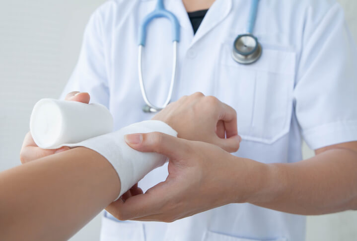 Doctor wrapping gauze over man's burn injury