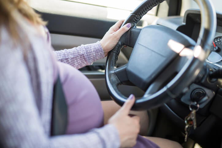 A pregnant woman driving a car