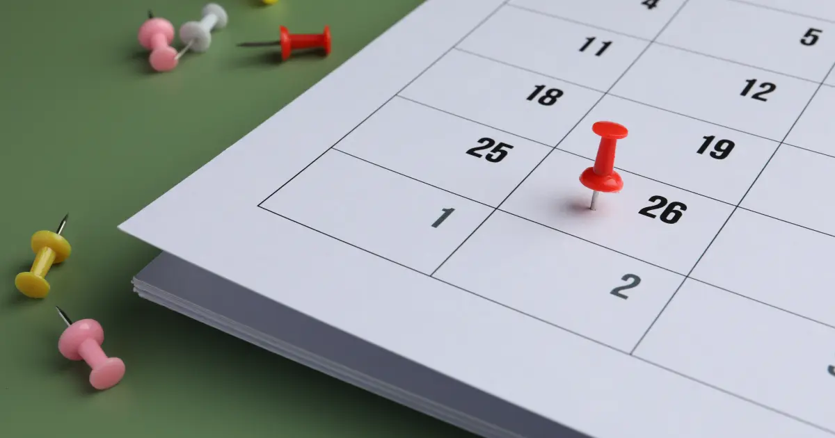 Calendario con un pin rojo marcando una fecha límite sobre un fondo verde